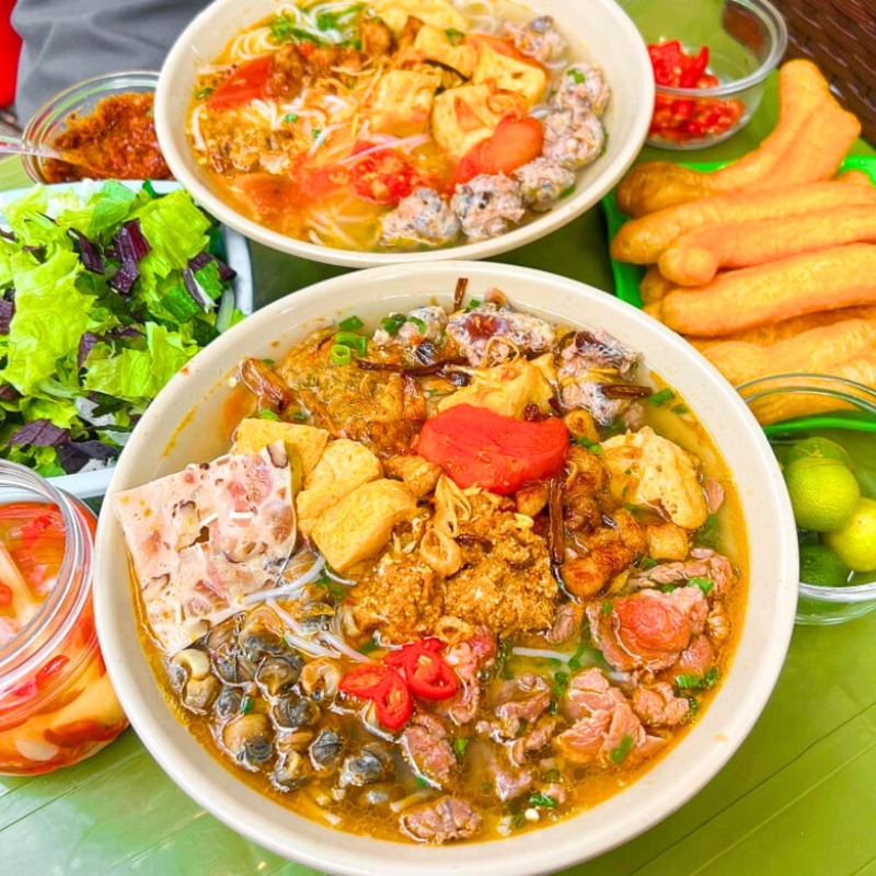 Le Bun riêu Hanoi est une soupe traditionnelle à base de crabe, avec un bouillon acidulé distinctif, offrant une saveur authentique