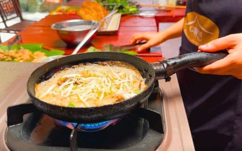 Déposez une portion de garniture et une poignée de germes de soja sur une moitié de la crêpe Banh Xeo